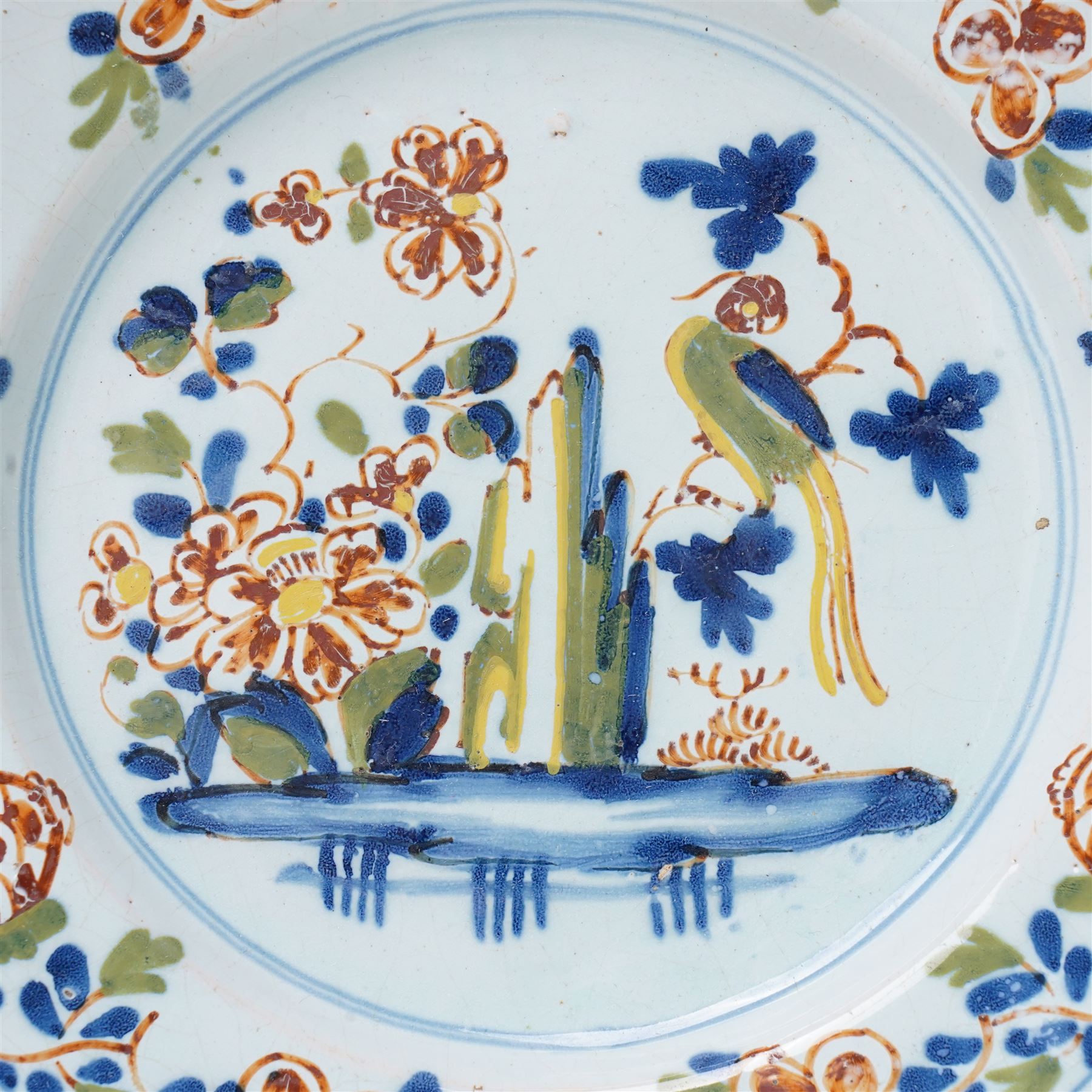 18th Century English Delft plate, probably Lambeth c1750, painted with a parrot on a branch among foliage, D22.5cm