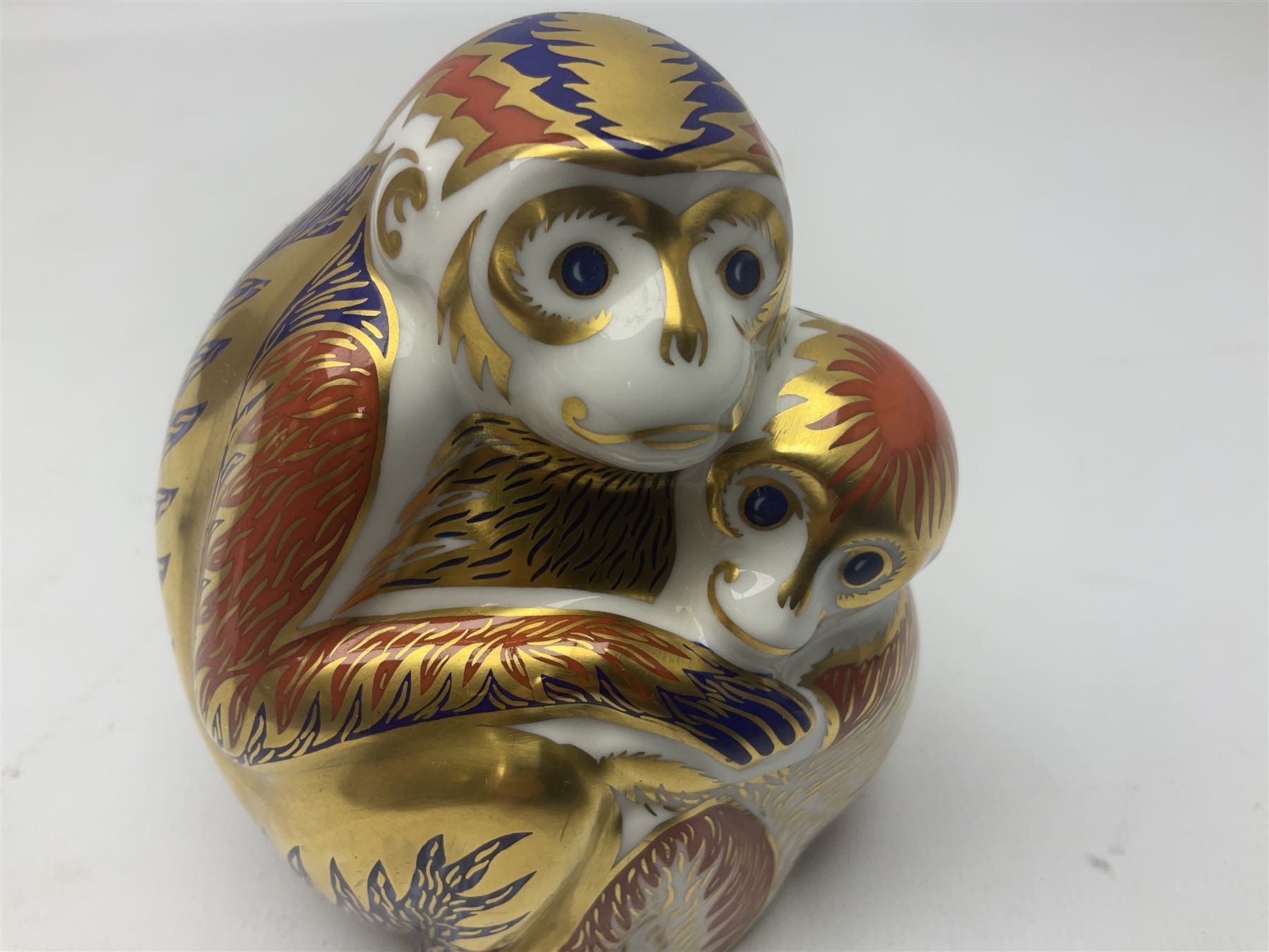 Three Royal Crown Derby paperweights, comprising Macaque, with gold stopper and original box, Monkey and Baby, with silver stopper and original box and Dragon with silver stopper, all with printed mark beneath  