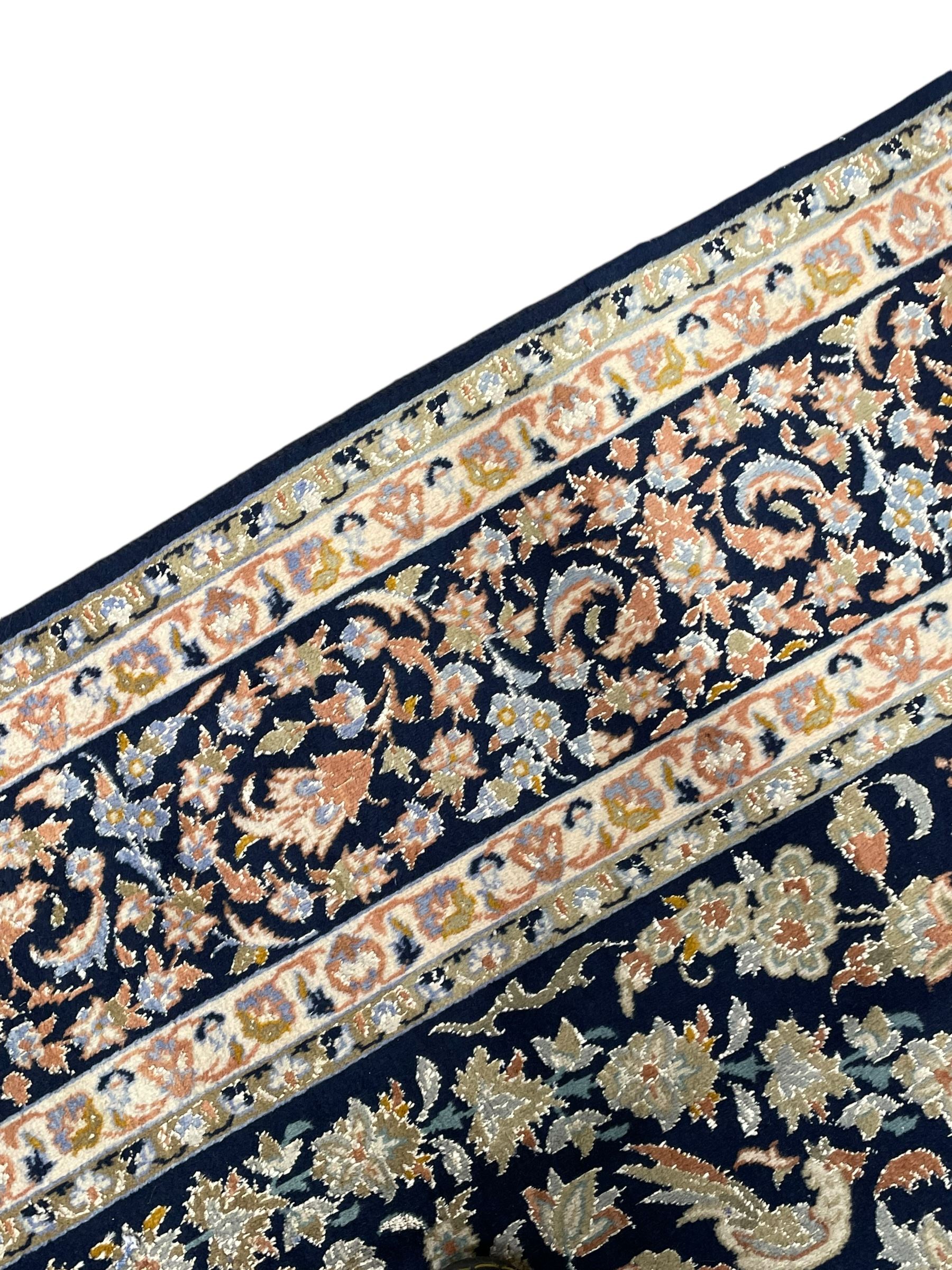 Persian Kashan indigo ground rug, the field consisting of trailing flower head bands and leafy branches, decorated with kuş or bird motifs, the border with repeating border containing curling leaves and flower heads, within guard bands 