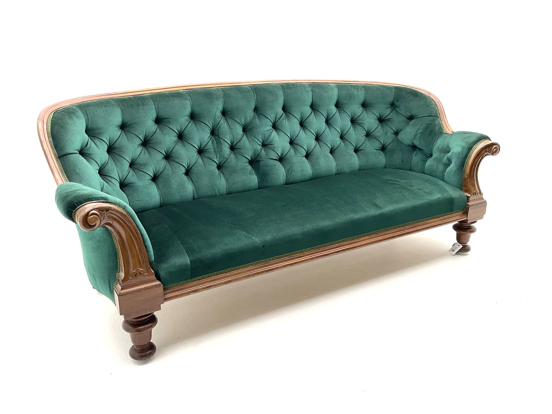 Victorian mahogany settee, upholstered in green buttoned fabric, moulded frame and scroll carved arm terminals, turned supports