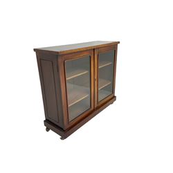 Victorian bookcase, rectangular top over two glazed doors enclosing two shelves, on skirted base