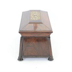Early 19th century rosewood and brass inlaid tea caddy, of sarcophagus form, the front and hinged opening cover inlaid with brass scrolling panels, opening to reveal a compartmented interior with twin removable boxes with conforming inlaid brass detail to the hinged covers and zinc lining to the interiors, flanking a later glass mixing bowl, the whole upon four turned cylindrical feet, H21cm W36cm D20cm
