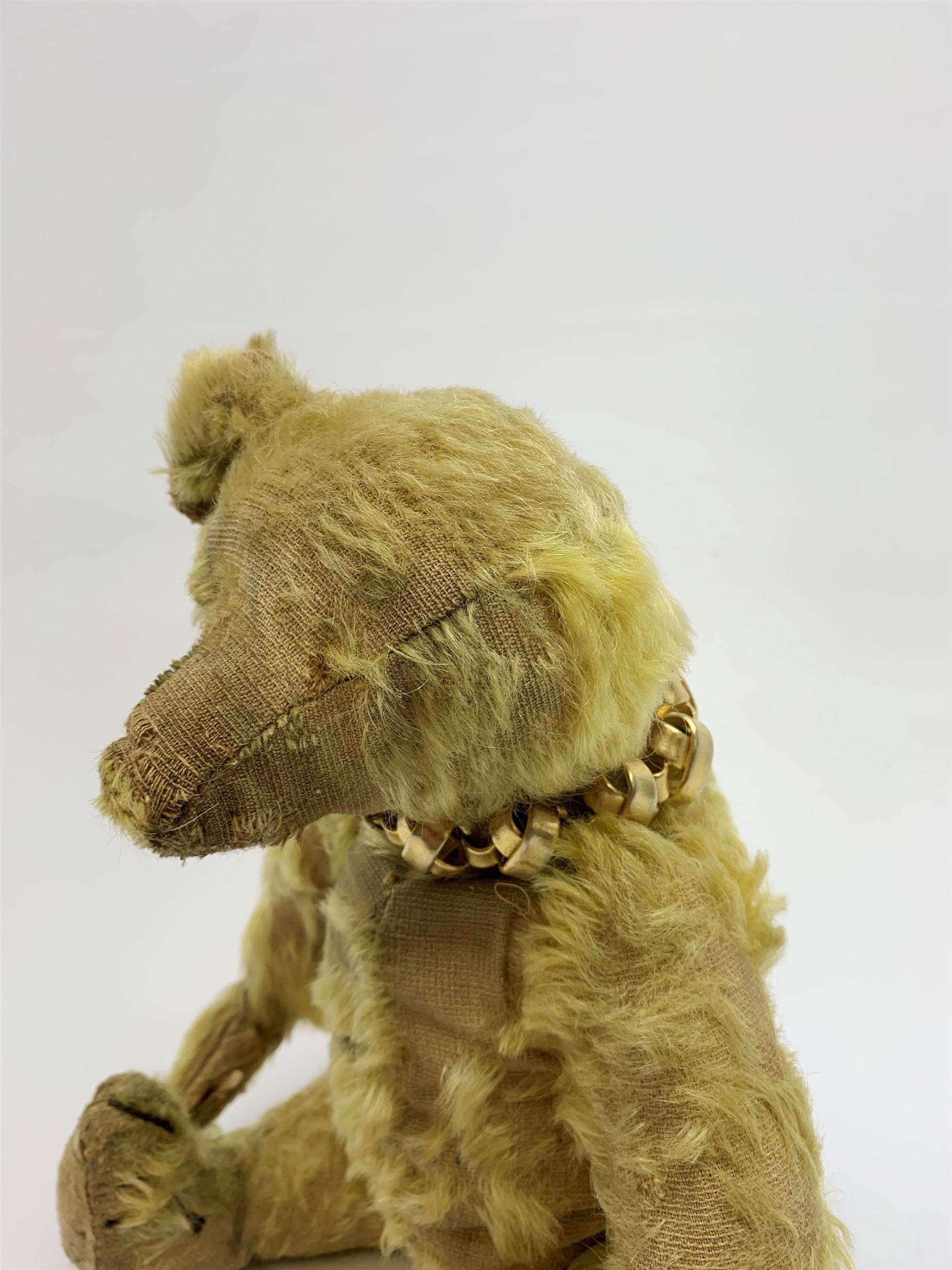 Early 20th century English teddy bear, with wood wool filled body with jointed limbs, felt covered paw pads, five claw stitching to feet and elongated arms with spoon shaped paws H14