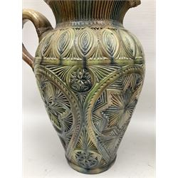 Early 20th century Royal Doulton stoneware vase, decorated with a stylized floral design below a wavy rim, monogrammed B.N, possibly for Bessie Newbery, H28cm, together with an early 20th century glazed jug, heavily carved throughout (2)