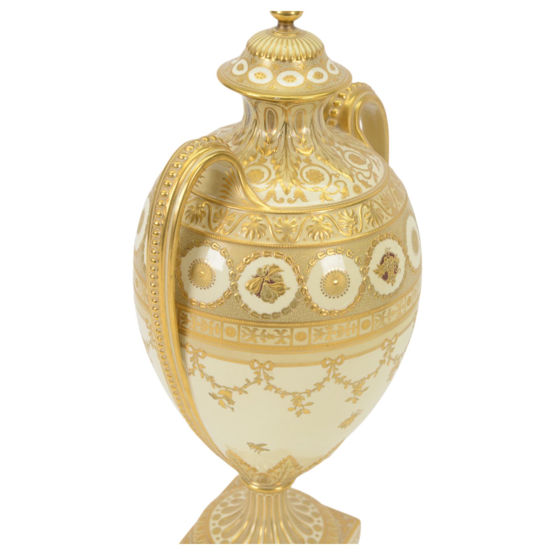 Royal Crown Derby twin handled vase and cover, circa 1886, decorated with raised and tooled gilt borders of foliate scrolls and husk swags upon a cream ground, H38cm