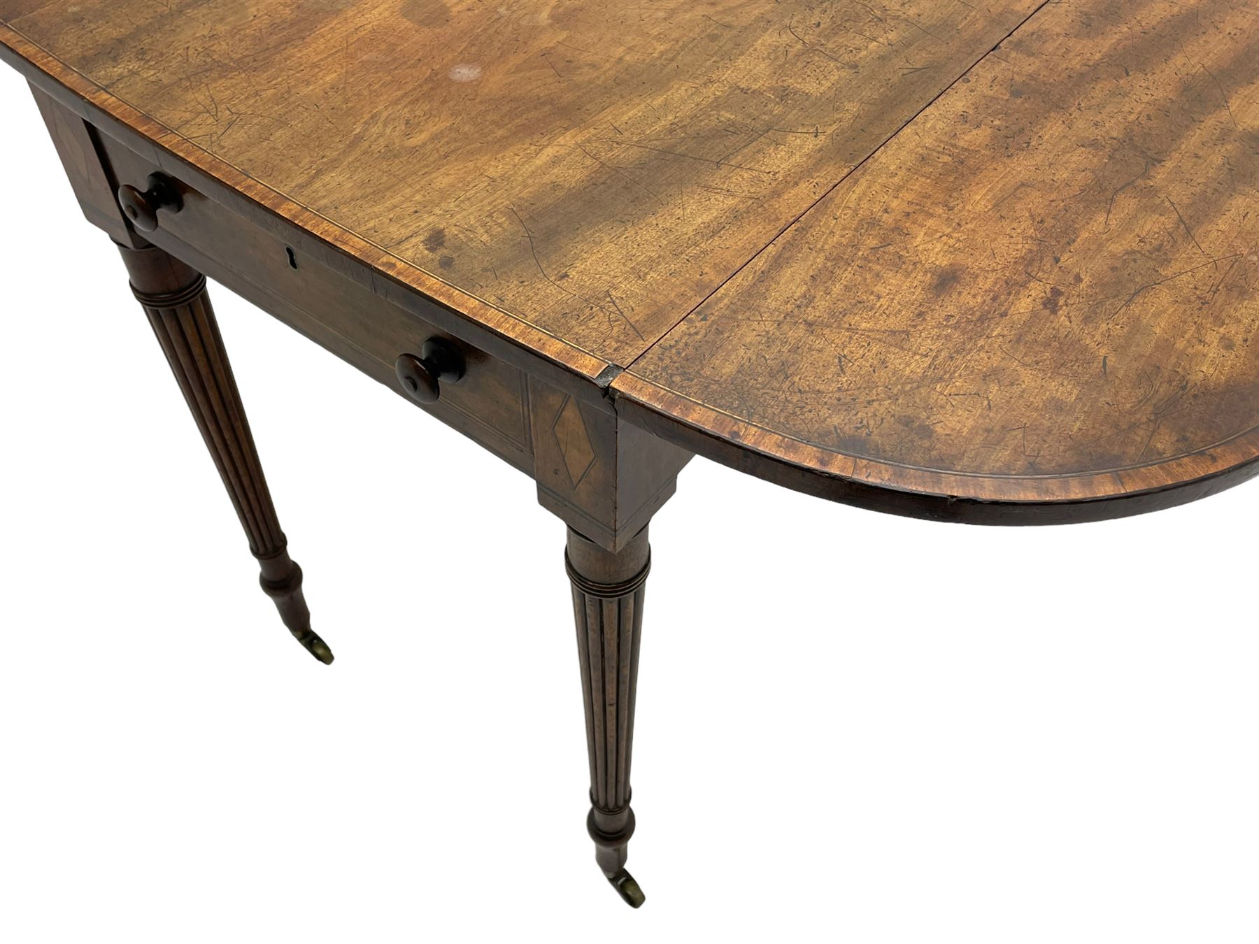 George III mahogany Pembroke table, drop-leaf oval top with satinwood band, fitted with single end drawer, inlaid with satinwood lozenge motifs, on turned and reeded supports with brass cups and castors