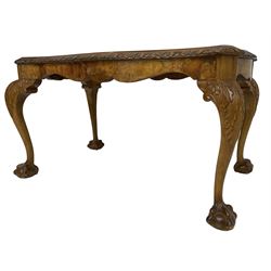 Mid-20th century figured walnut serpentine coffee table, inset glass top and foliate carved edge, raised on cabriole supports with acanthus moulded knees and ball and claw feet
