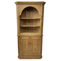 Waxed pine floor standing corner cupboard, projecting cornice over two open shelves flanked by turned uprights, base fitted with cupboard enclosing single shelf