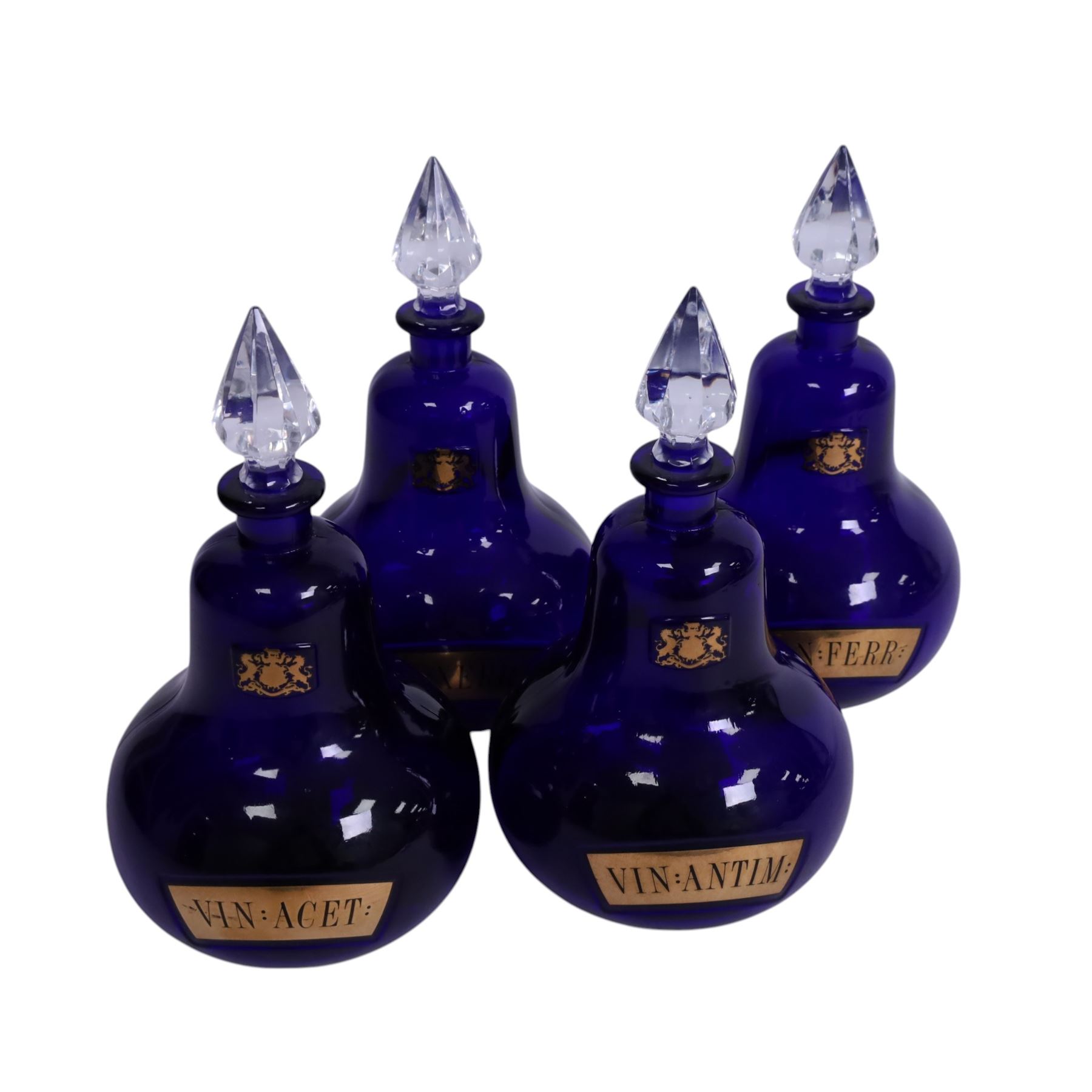 Set of four 20th century Royal Pharmaceutical Society blue glass bottles, of bellied form with clear cut glass spire stopper, each body bearing gilt label in Latin: VIN:ACET:, VIN:ANTIM:, VIN:XERIC:, and VIN:FERR:, and gilt Royal Pharmaceutical Society crest to neck, H25cm

Provenance: From the collection of the family of Peter Green, a practising pharmacist whose career spanned the mid to late 20th century. During his professional life he managed pharmacies in Yeovil, Somerset, and later Selles Chemist in Filey, North Yorkshire, before purchasing and running his own business, Peter Green Pharmacy, located in the Market Place, Malton. The bottles were displayed as part of the traditional shop fittings in both the Filey and Malton pharmacies and were retained as part of his collection.