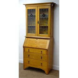 Early 20th century light oak bureau bookcase, stained and leaded glass doors enclosing two adjustable shelves above fall front with fitted interior, three graduating drawers W91cm, H194cm, D39cm  