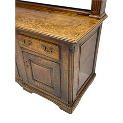 George III oak dresser, projecting dentil cornice over three heights plate rack enclosed by fluted uprights, the dresser fitted with five drawers and two panelled cupboards, canted corners with fluted quarter columns, on bracket feet