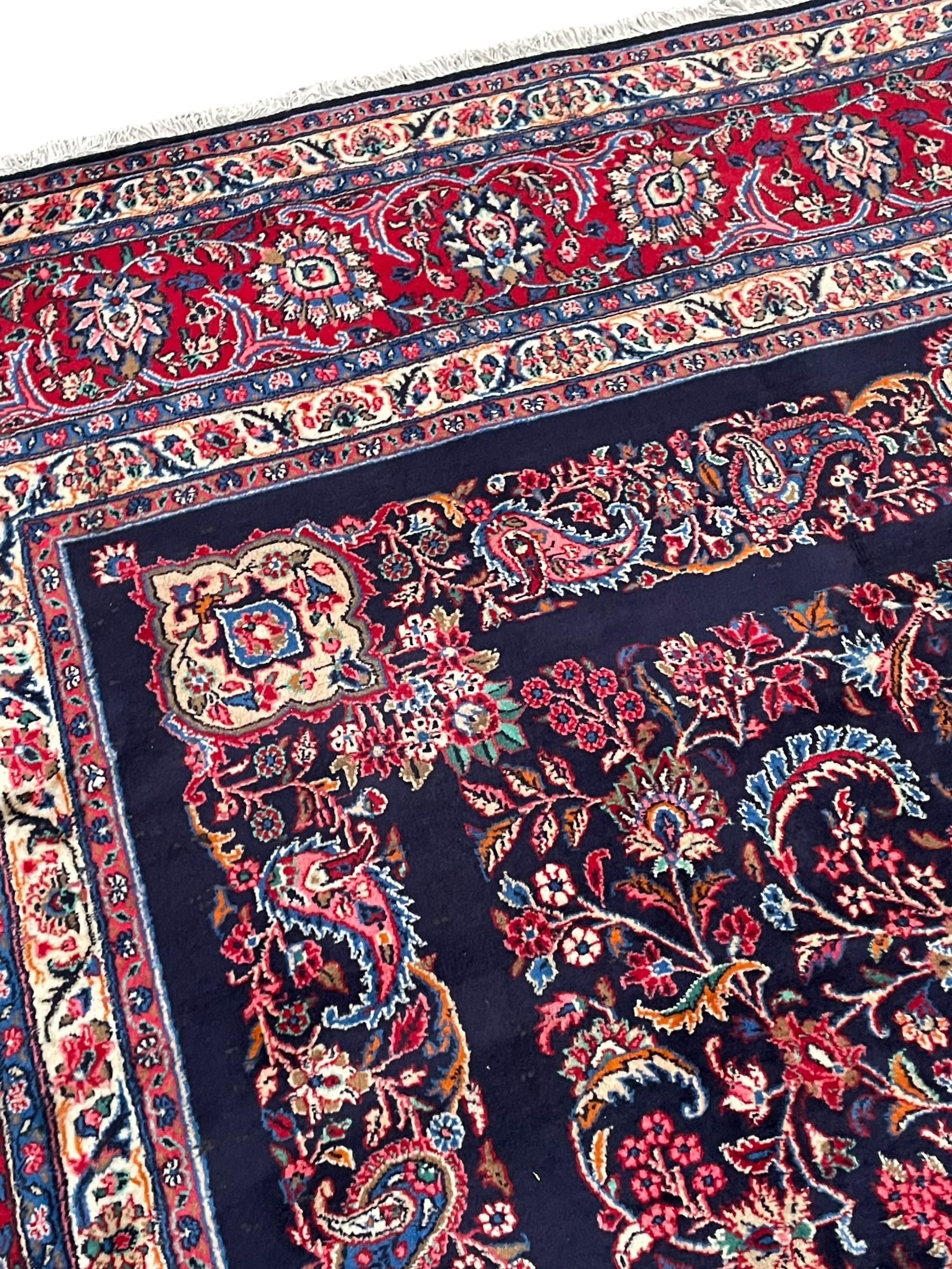 Persian Hamadan indigo ground carpet, the field decorated with central rectangle and outer band, overall floral pattern with cusped central medallion and surrounding leafy branches with palmettes, the border with scrolling branches decorated with further palmettes, within floral pattern guard stripes
