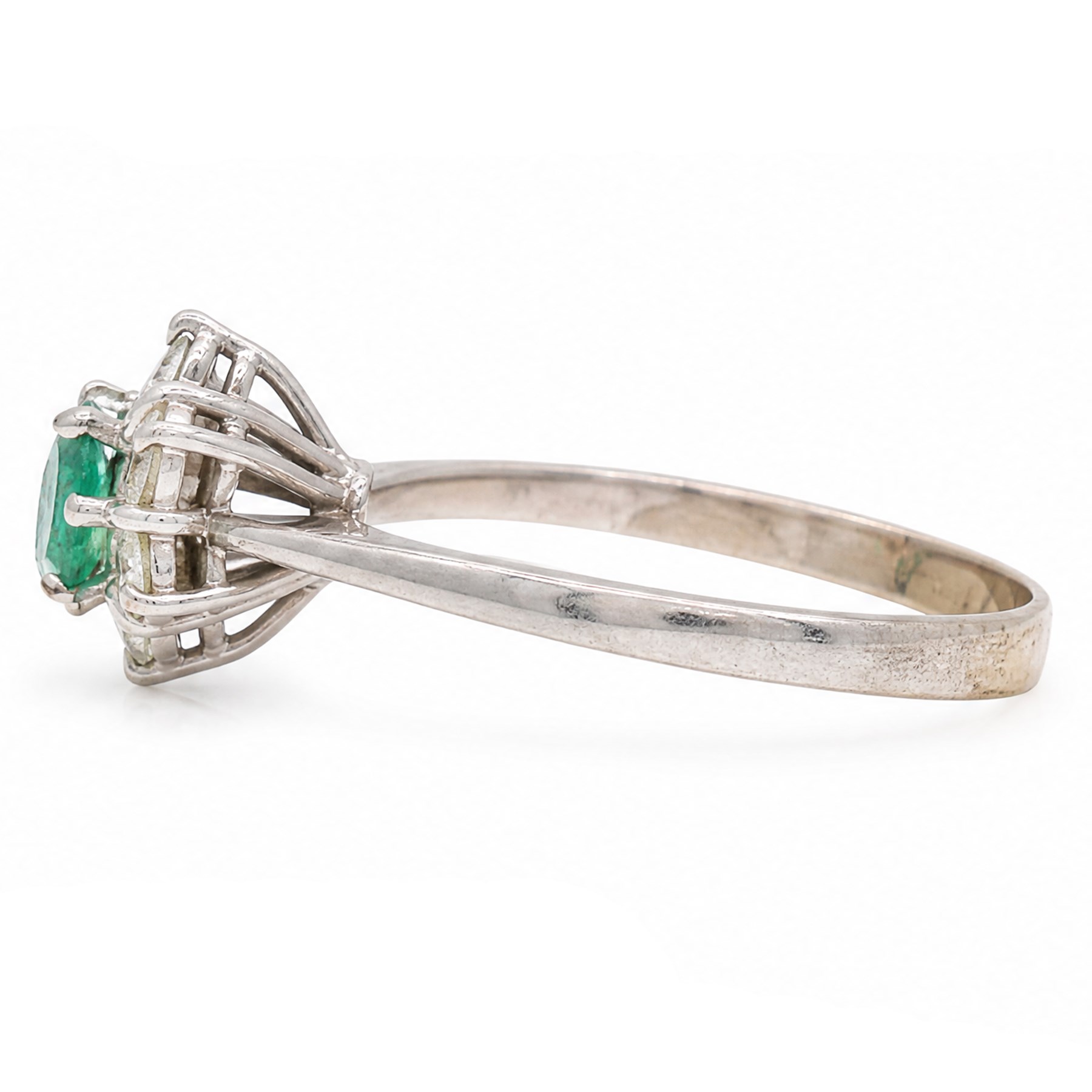 White gold emerald and diamond cluster ring, single oval cut emerald of approx 0.25 carat, surrounded by six round brilliant cut diamonds, stamped, total diamond weight approx 0.30 carat