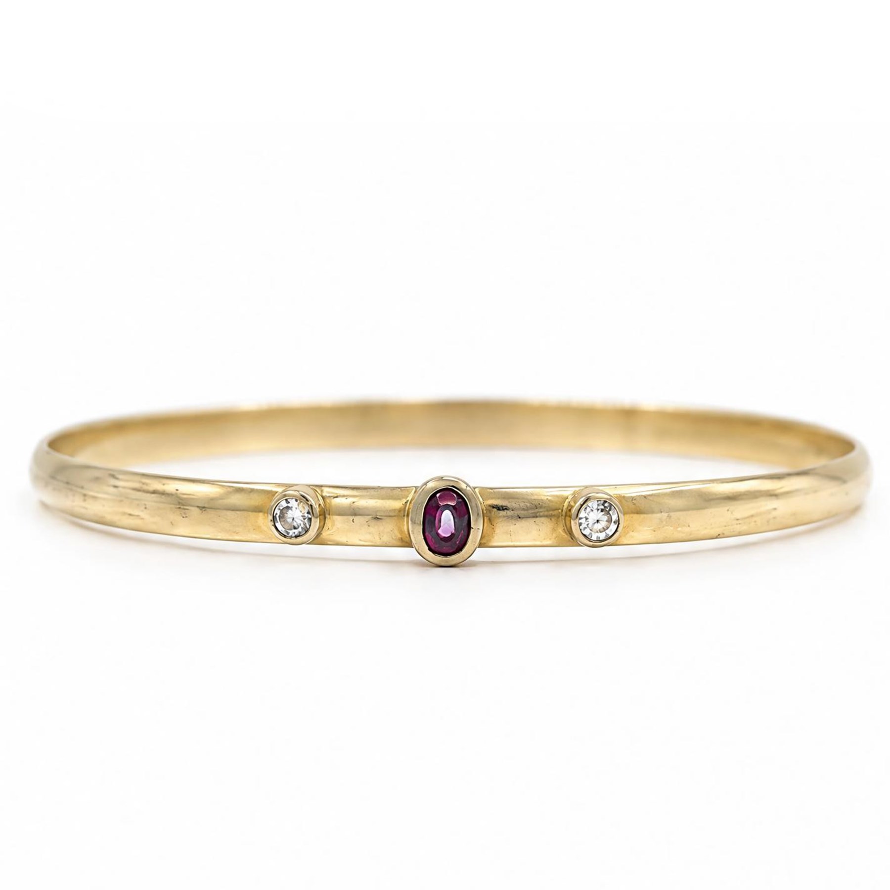 18ct gold ruby and diamond bangle, single oval cut ruby set between two round brilliant cut diamonds, stamped 750
