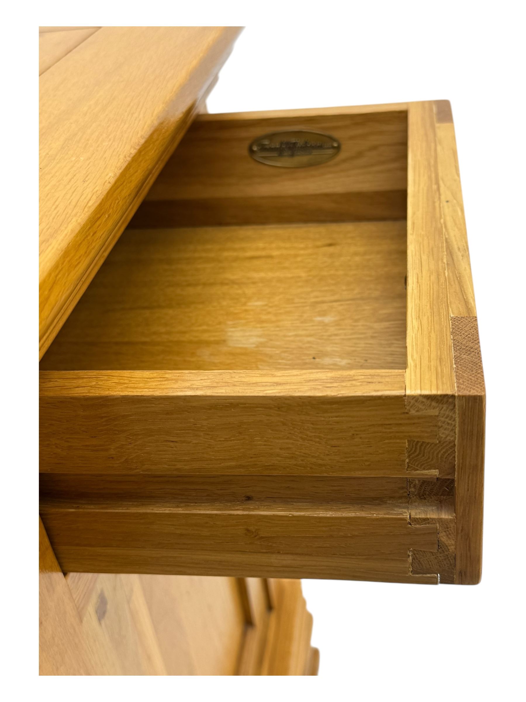Frank Hudson - contemporary pair of light oak bedside cabinets, each with moulded rectangular top over single drawer above cupboard door with arched panel, on a moulded plinth base with bracket feet