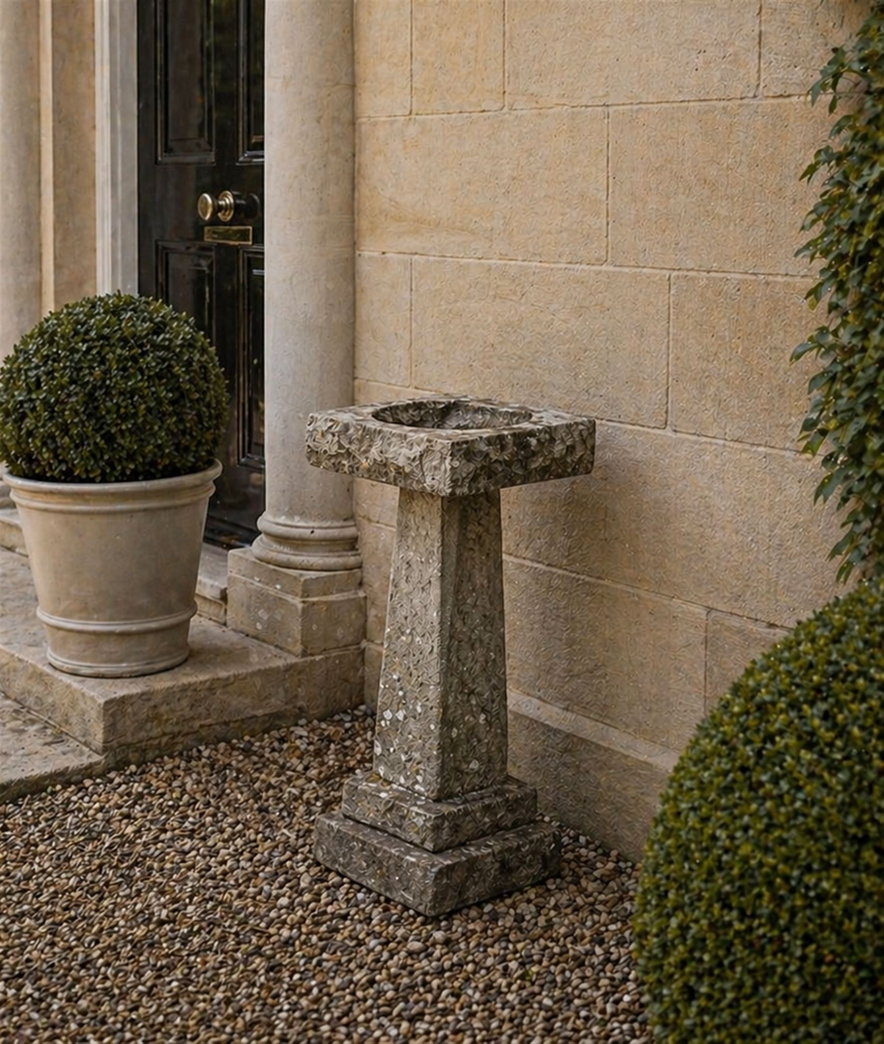19th century weathered sandstone birdbath, formed in four sections, square top with carved shell bath, raised on tapering column with stepped base