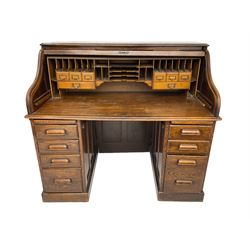Early 20th century oak twin pedestal desk, tambour roll top enclosing small drawers and correspondence pigeon holes, fitted with seven drawers and two slides, on plinth base