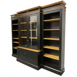 Contemporary polished pine and black finish break-front bookcase, projecting cornice over globular mounts, central cabinet enclosed by two glazed doors over double panelled cupboard, flanked by adjustable shelves, on plinth base