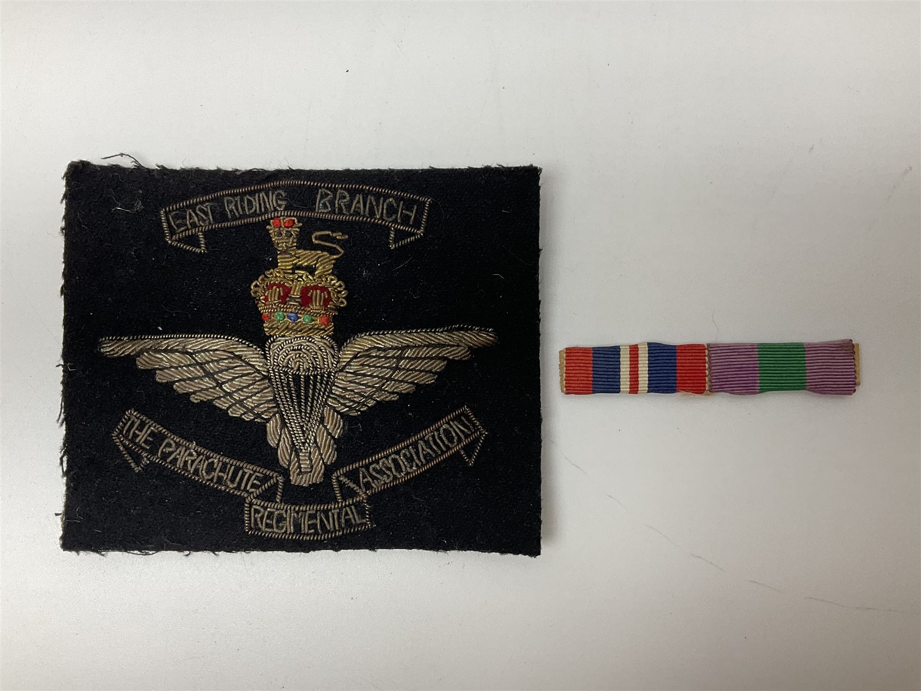 Parachute regiment - chrome crest on oak easel shield; three cloth badges; small silver plated figure; and pin badge; together with 10cm diameter cannon ball etc