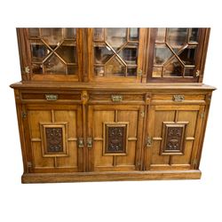 Edwardian mahogany bookcase on cupboard, projecting cornice over three astragal glazed doors with mouldings and bevelled glass, moulded uprights and carved with flower head roundels, the lower section with moulded rectangular top over three drawers and three cupboards, the doors panelled and carved with foliage scrolls and urns, plinth base