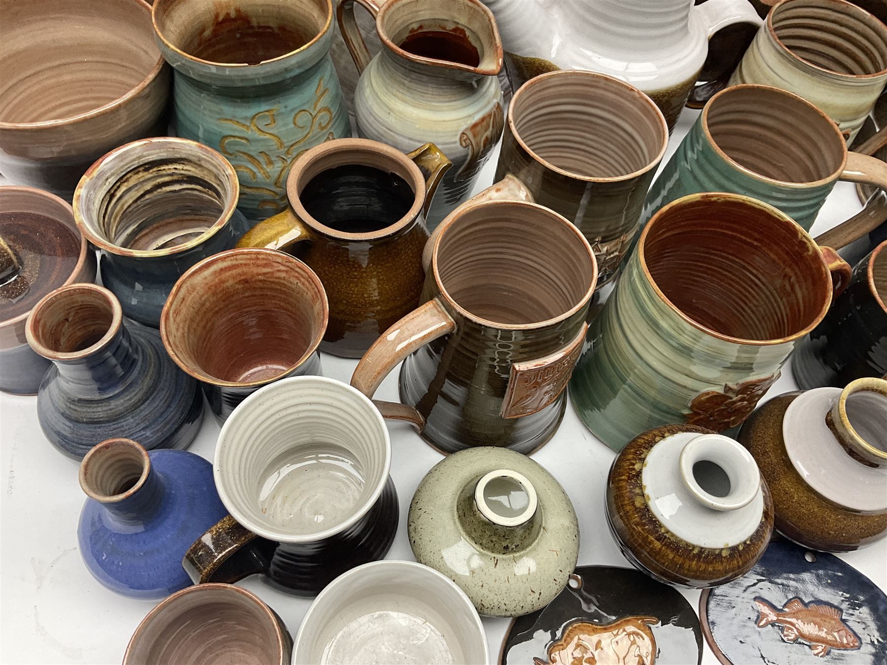 Wold studio pottery tankards, in various colours and relief decoration together with other studio items including vases, jugs and pots 