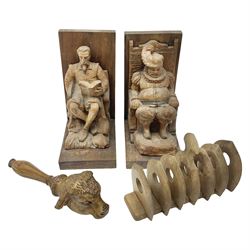 Pair of continental carved fruitwood figural bookends, H19cm, together with a carved wooden bulls head nut cracker and an Arts and Crafts style wooden seven bar toast rack