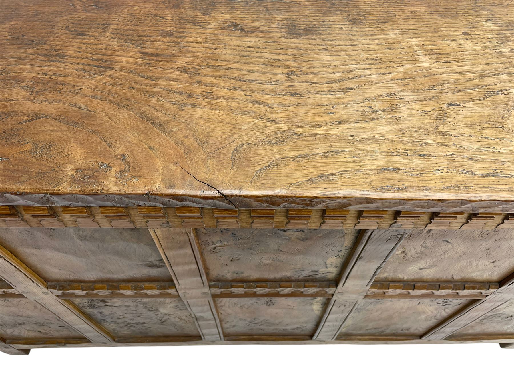 Gnomeman - oak blanket box, all-over adzing, the hinged top over figured and burr panelled front, decorated with carved crenellations and arcade, carved with gnome signature, pierced handles to each end forming the central rail, wrought metal hinges, on stile supports, by Tom Whittaker, Littlebeck, Whitby