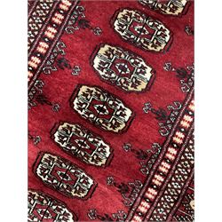 Persian Bokhara rug, red ground and decorated with single row of Gul motifs, multiple band border with geometric design
