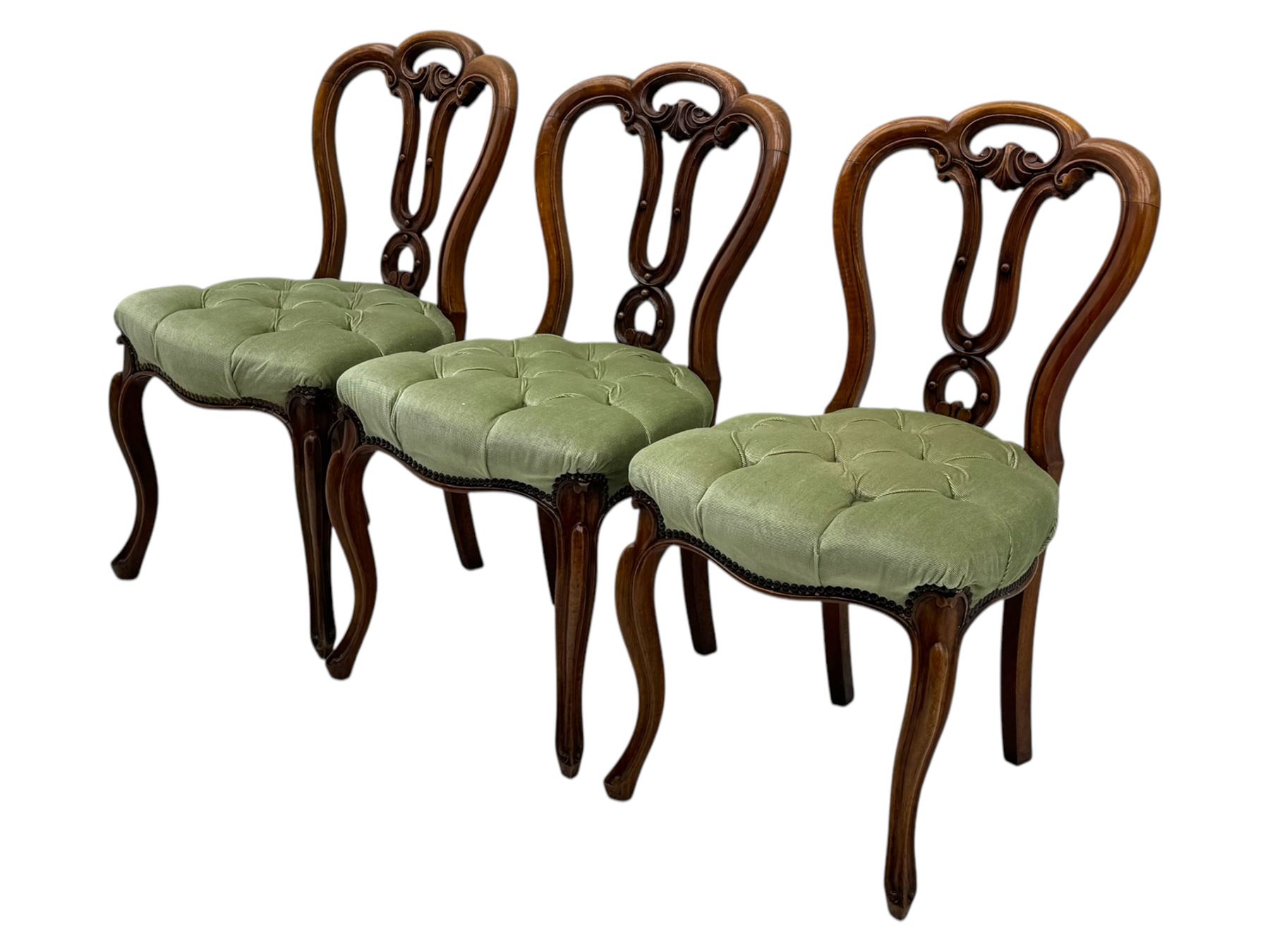 Set of six carved Victorian walnut balloon back dining chairs, button upholstered in green velvet fabric, back with foliate carved decoration supported on scroll form legs 