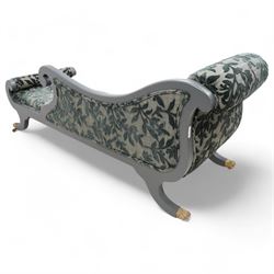 Regency design hardwood-framed chaise longue, scrolled back upholstered in leafy branch pattern fabric, reeded and scroll carved frame, on out splayed feet with brass paw castors