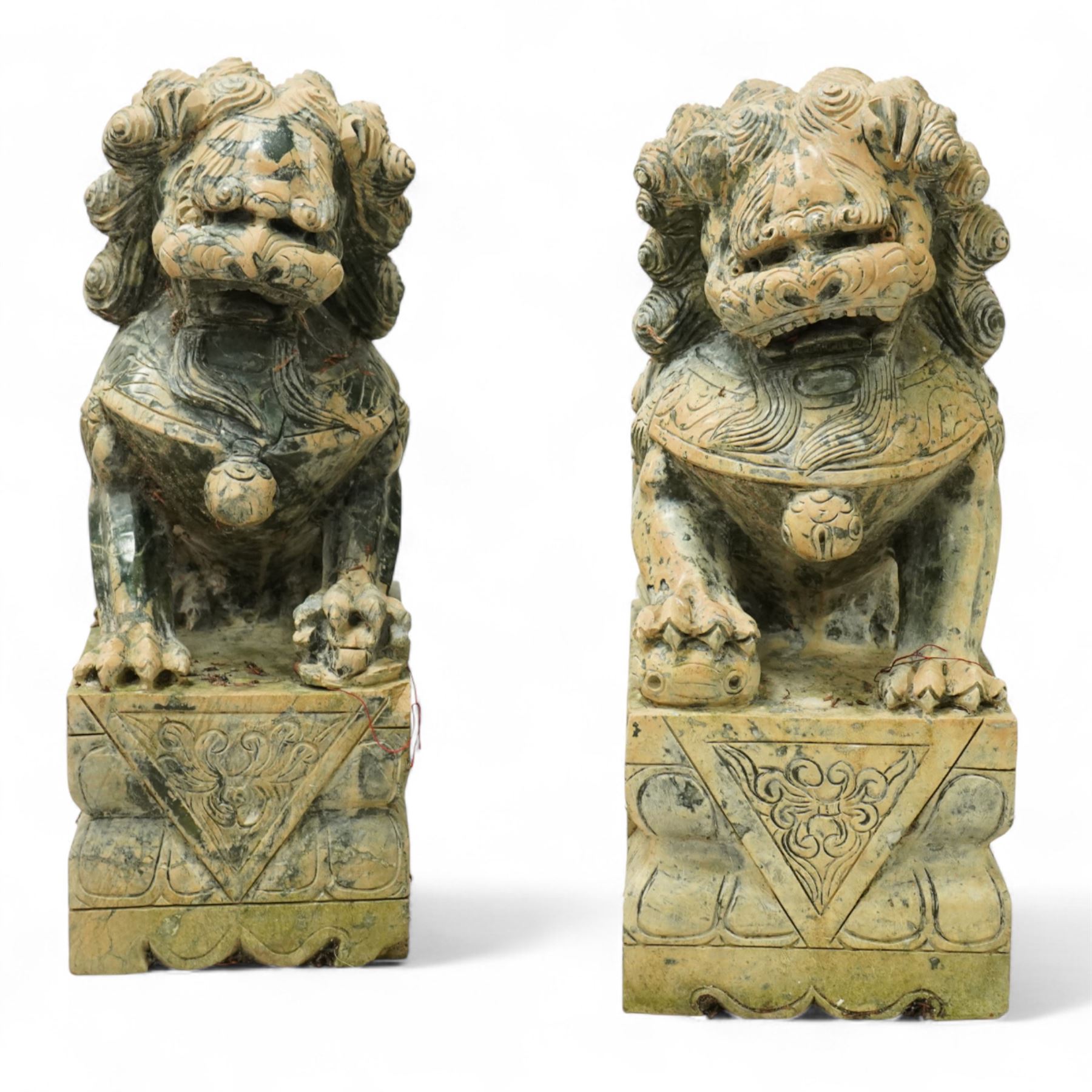 Pair of Chinese hardstone carved Foo dogs, each finely carved seated on rectangular plinth bases with detailed manes, collars and bells, the male with paw resting on a ball, the female with cub, in mottled green stone resembling jade