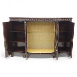 Edwardian mahogany serpentine breakfront display cabinet in the neoclassical style, the rectangular top above a carved frieze with roundels, foliage, and ribbon tied swags with central bow-fronted astragal glazed doors enclosing shelves, flanked by panelled doors, raised on bracket feet 