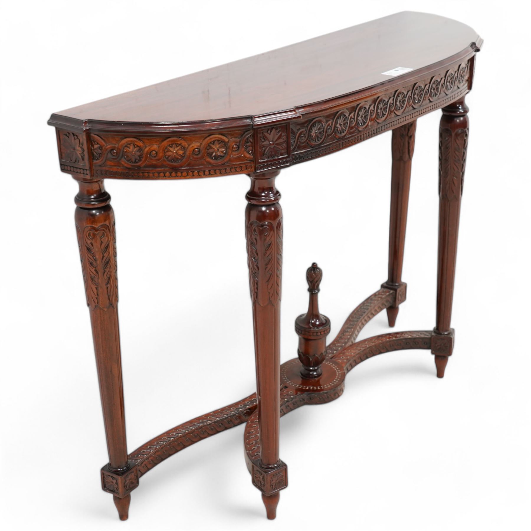 Mahogany demi-lune console table, moulded top over flower head guilloche decorated frieze, on turned and acanthus carved supports with fluted decoration, united by shaped stretchers with central finial 