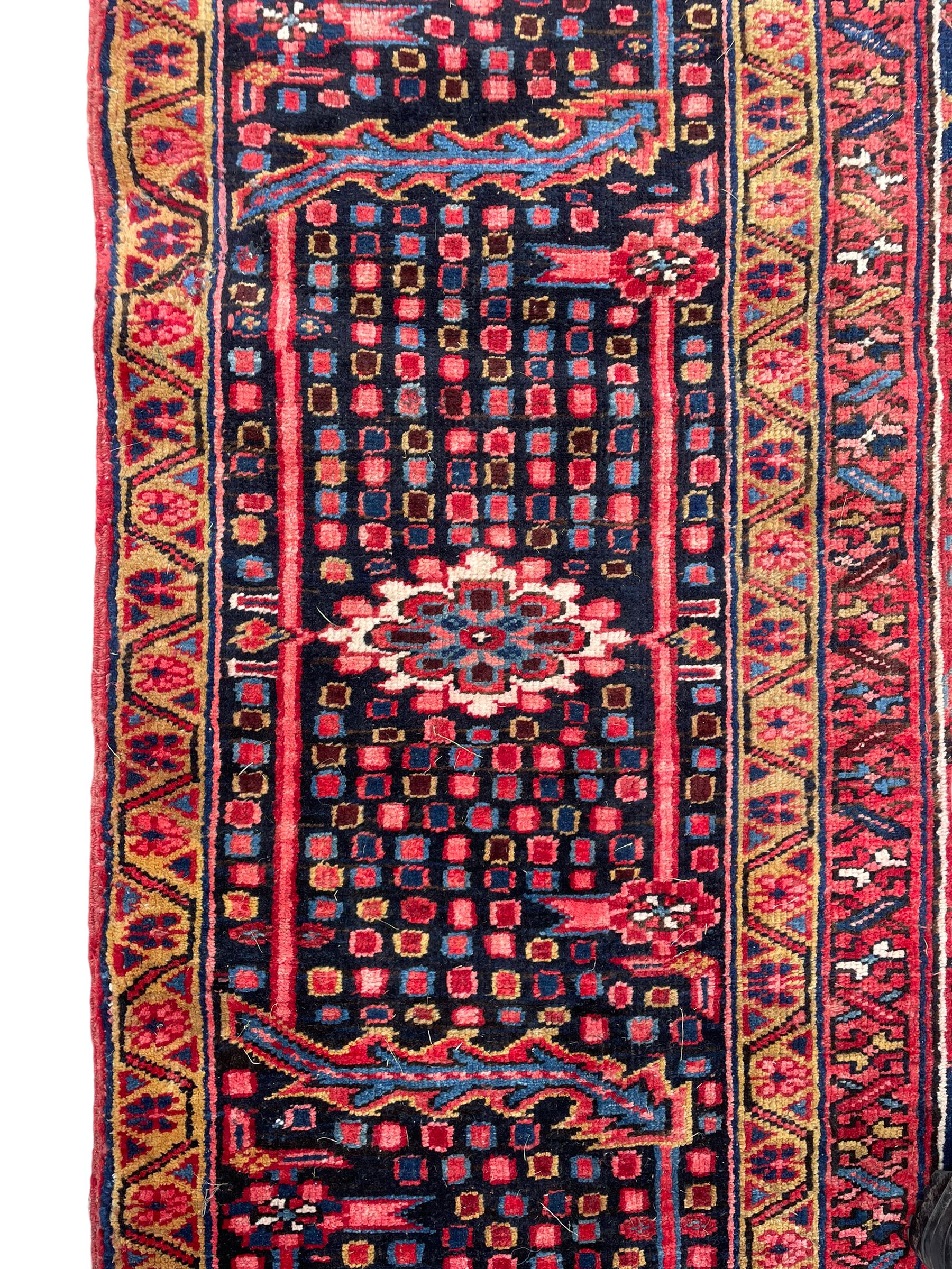 Antique Persian coral ground carpet, the large central floral pole medallion with extending foliate designs, the thick guarded indigo border with repeating flower heads and circles