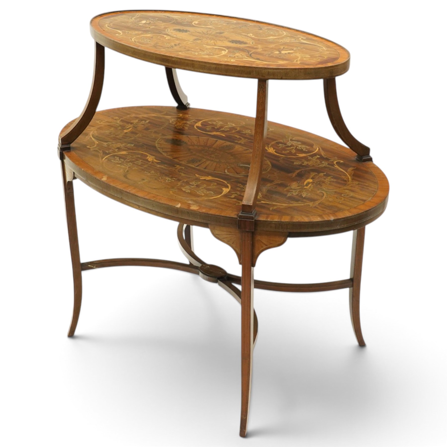 Edwardian Sheraton Revival inlaid mahogany and satinwood marquetry oval two-tier étagère occasional table, the oval top with removable glazed tray with brass handles, over an ornately inlaid top with central patera motif and trailing foliate scrolls, the splayed uprights inlaid with bellflowers, over a matched inlay under-tier, raised on splayed supports united by curved X-stretcher,  retailed by David Hick Interiors, Jersey