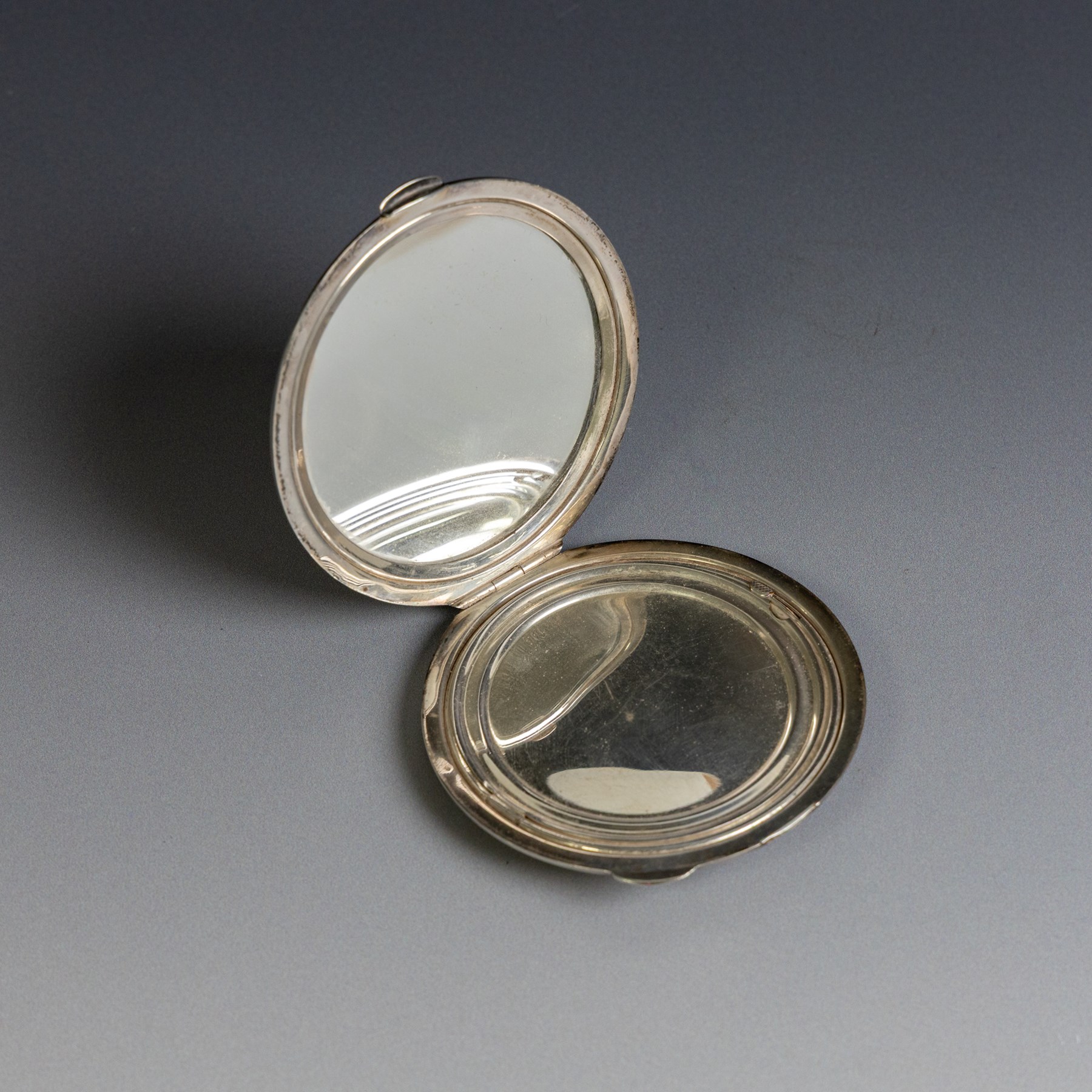 Two silver compact mirrors, comprising a Kigu powder compact with engine turned decoration and a compact mirror with floral decoration, both hallmarked