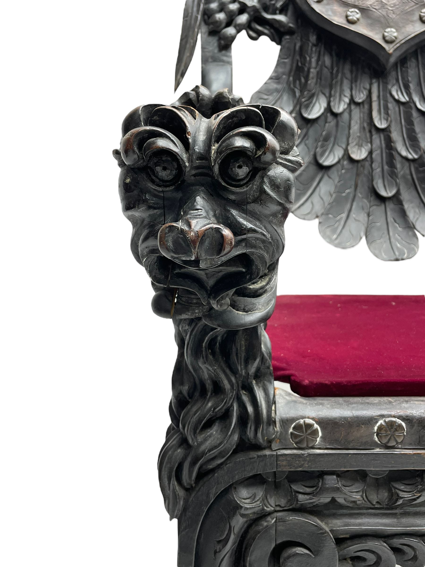 Grand mid-to-late 19th century heavily carved beech framed throne chair, the crown pediment carved with flower heads and cross finial, scroll and acanthus carved upright supports with twin perching griffin back enclosing etched leather work heraldic shield with castle and lion motifs over splayed feathers, flower head carved down sweeping arms with grotesque carved terminals, the seat rails carved with further flower heads on moulded supports with oversized ball and claw carved feet

Provenance: A very similar chair was used in the filming of Stanley Kubrick's 'Eyes Wide Shut' (1999)
