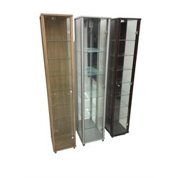 Three narrow glazed display cabinets, single glass door enclosing glazed shelves 