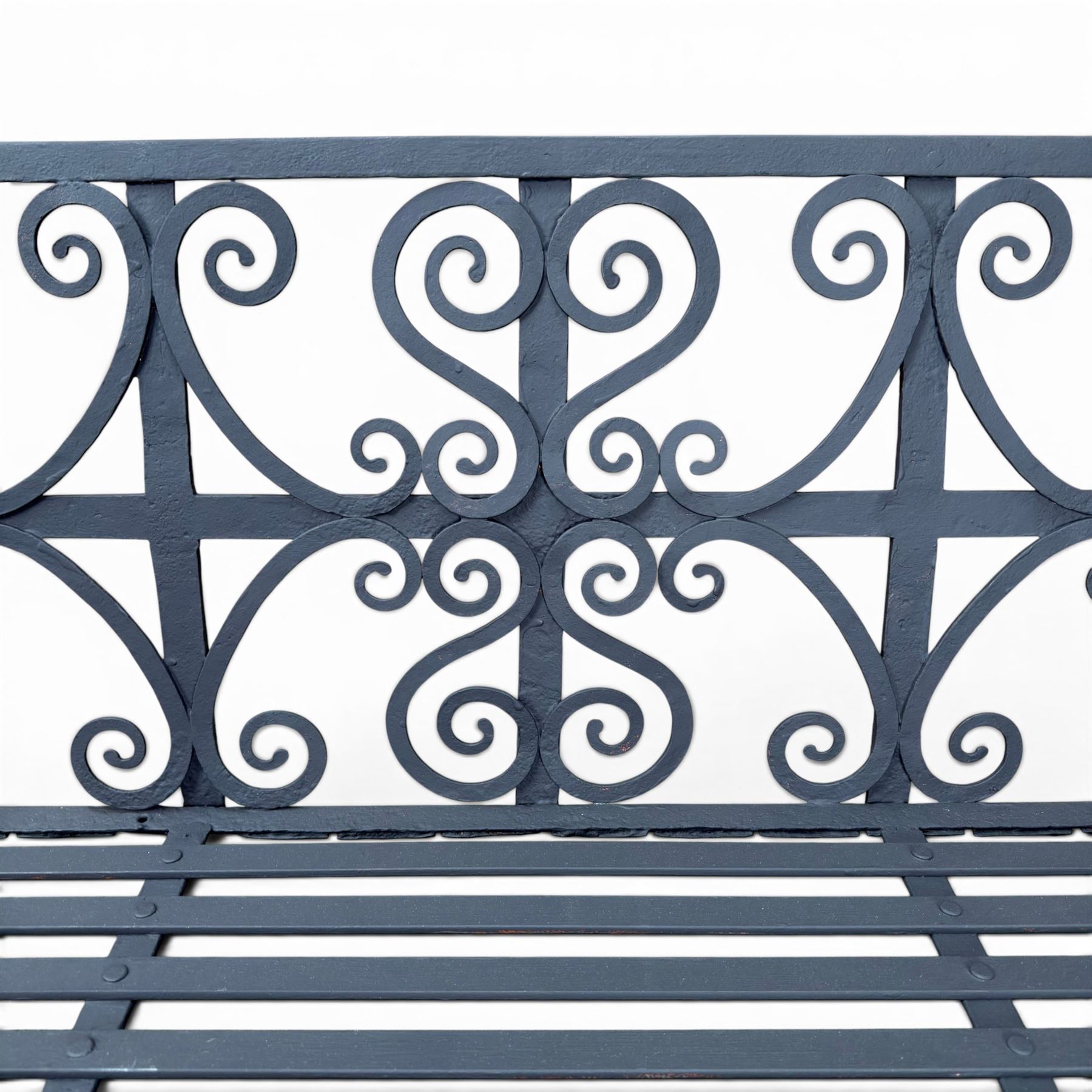 Regency period wrought iron garden bench, hand forged in wrought iron and finished in matt black paint, decorated with intricate scrollwork and featuring circular geometric ends, strapwork seat