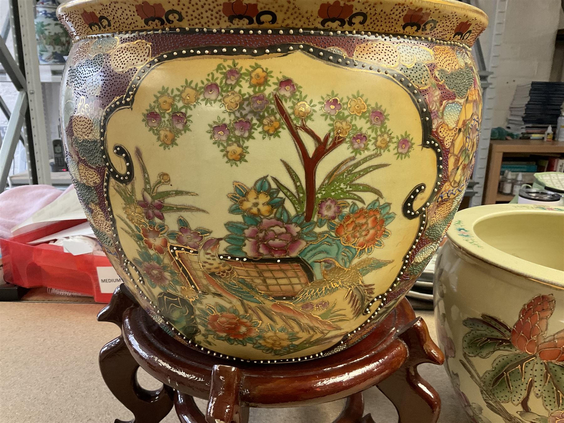 20th century Oriental fish bowl jardinière, decorated with reserves of birds amongst flowers, on wooden stand, fish bowl H29cm D36.5cm, together with another smaller example 