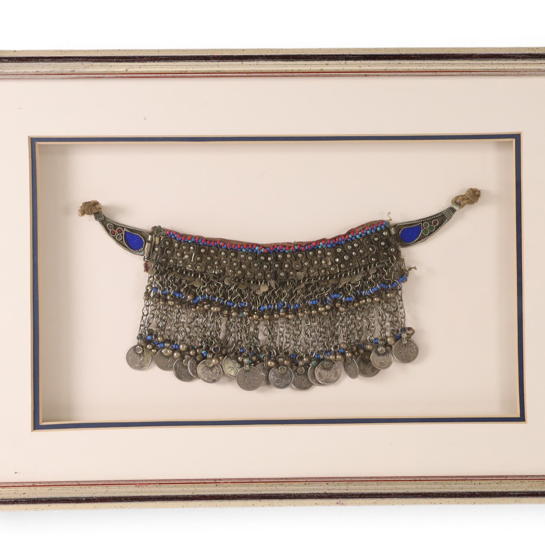 Four framed pieces of jewellery, including tribal coin and blue stone choker, multi stand necklace with turquoise beads and two box pendants 