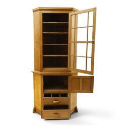 Acorn Industries - oak floor-standing corner cabinet, the top fitted with astragal glazed door enclosing four shaped shelves, the base with single panelled cupboard over two drawers, raised on four stepped feet, carved with acorn signature to top and base, by Alan Grainger, Brandsby