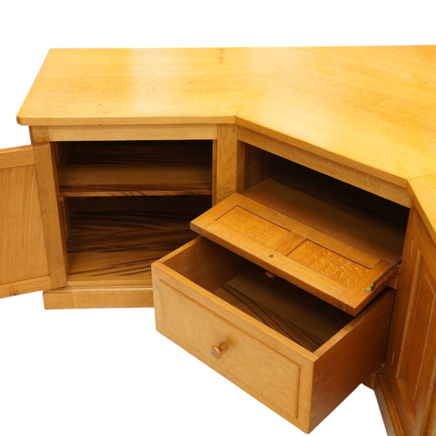 Seahorseman by Shaw & Riley - bespoke large Yorkshire oak corner sideboard or media unit, of L-shape form, with three cupboard doors, a fall front drawer over a regular drawer, a lift up panel for a record player, multiple apertures for wires, raised on a plinth base, with signature Seahorse carving from the workshop of A. Shaw & Riley Ltd, Hessay