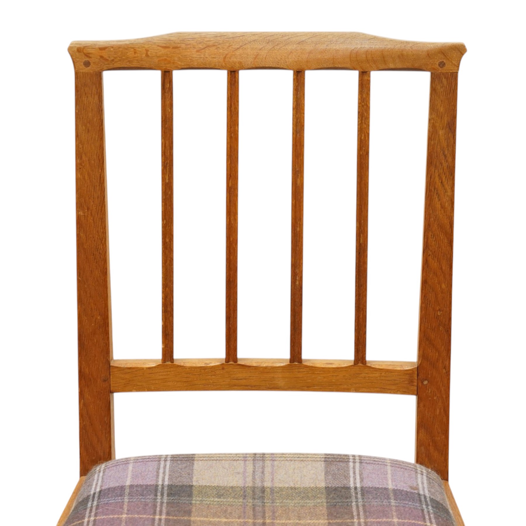 Acorn Industries - set of eight oak dining chairs, the shaped cresting rail over a fluted stick back, the drop-in seats upholstered in contrasting form with four pale mauve and four in purple tartan, raised on square supports, carved with acorn signature, by Alan Grainger, Brandsby