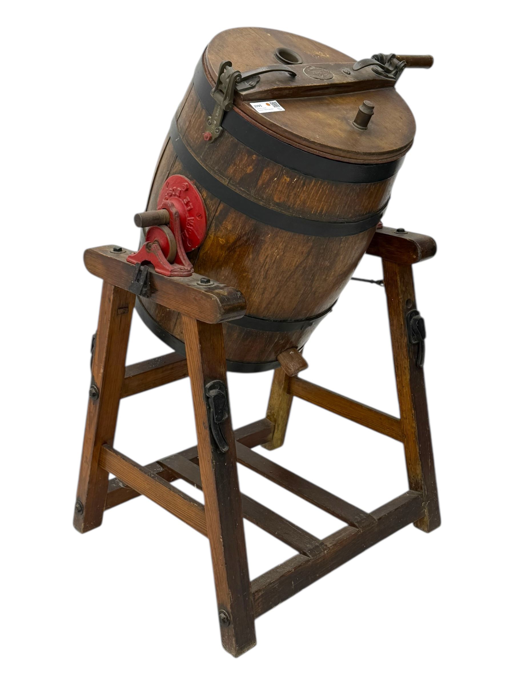19th century oak and cast iron rotary butter churn, with coopered barrel body, domed lid with filler opening and cast iron securing arms, on tilting iron-mounted frame with crank handle and support rails