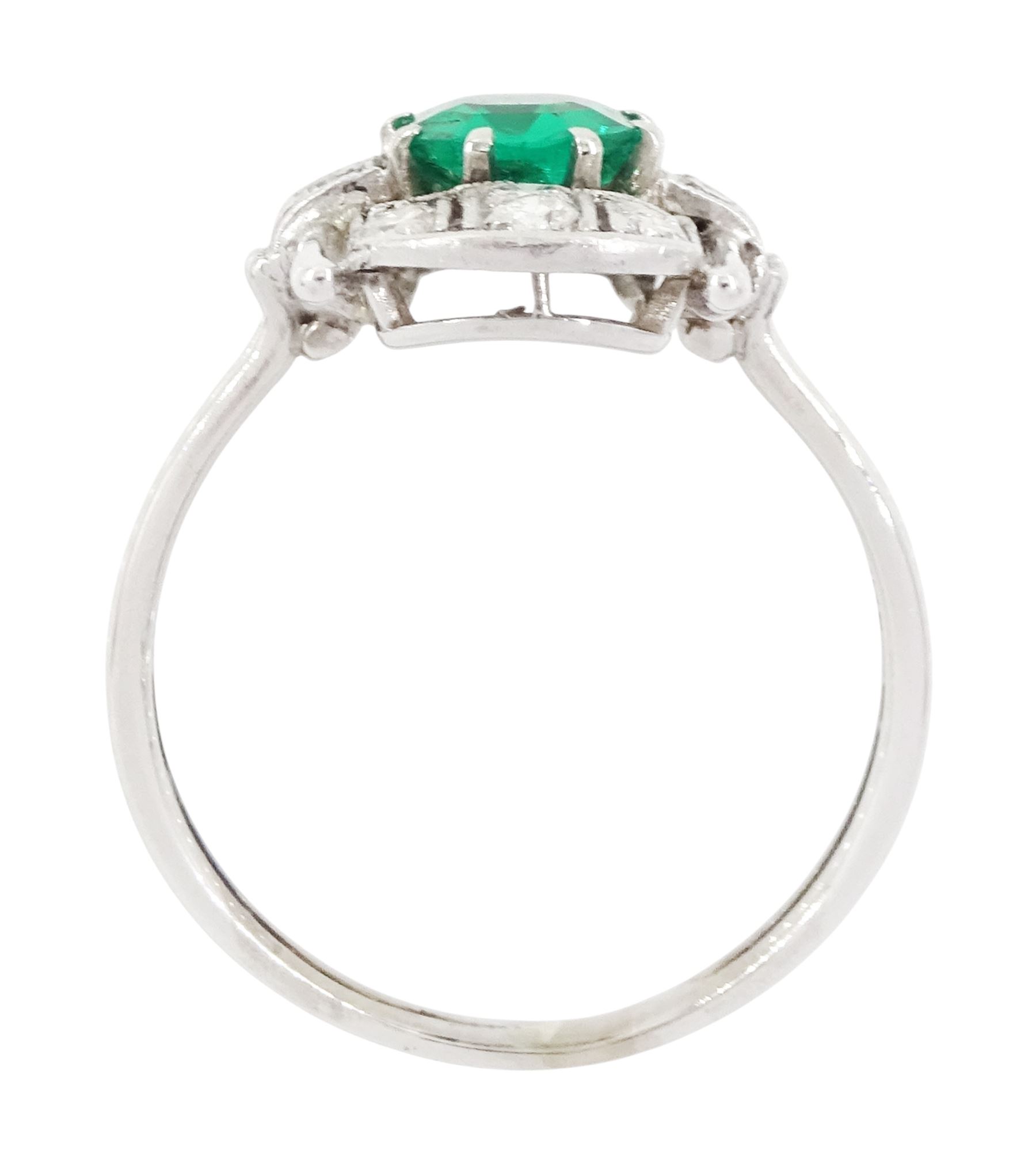 Art Deco 14ct white gold emerald and diamond panel ring, the central round cut emerald of approx 0.45 carat, within a pierced octagonal setting, flanked by a single cut diamond either side and three rows of milgrain set, single cut diamonds, to a reeded shank, stamped 585, total diamond weight approx 0.55 carat