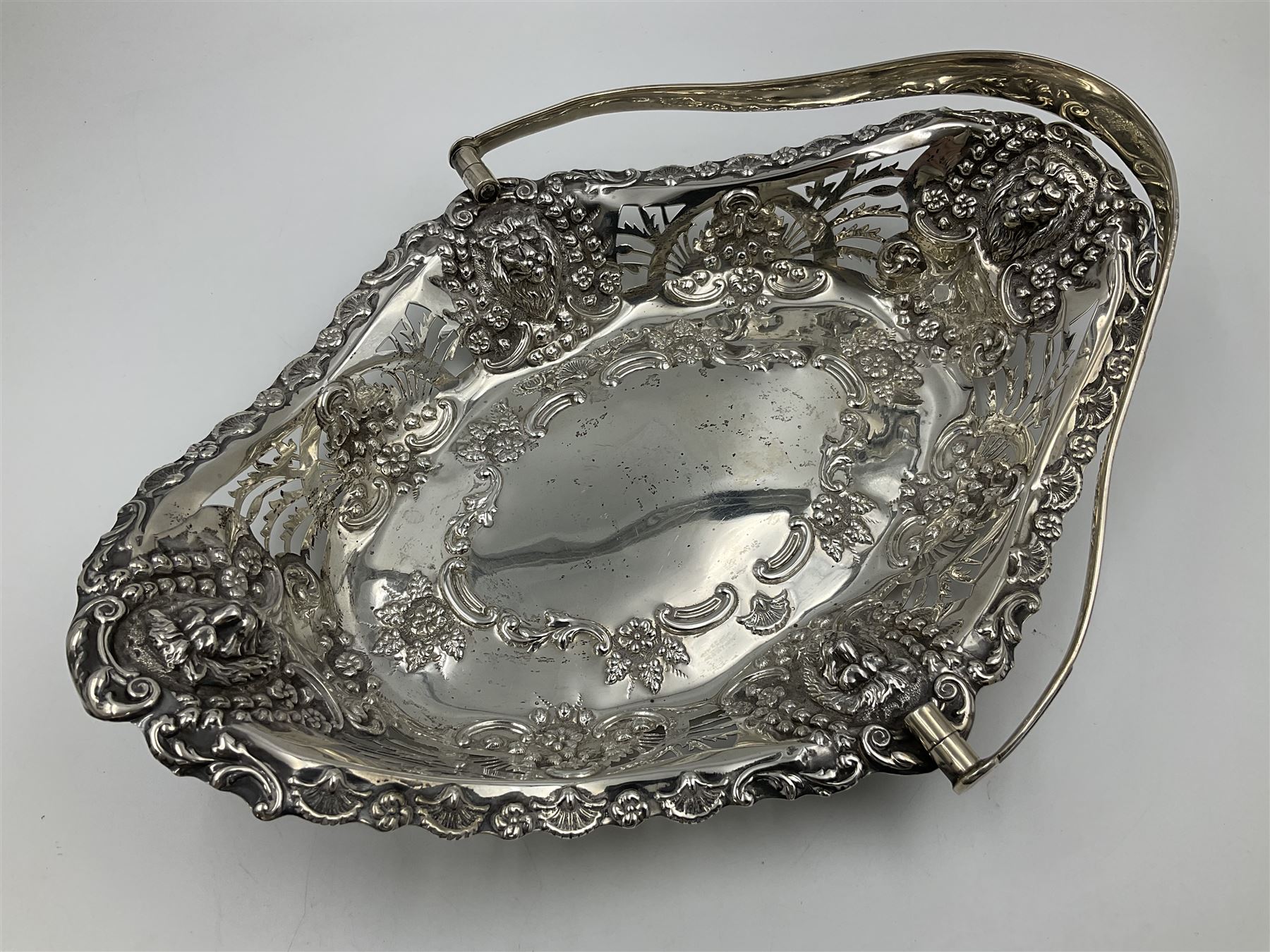 Edwardian silver swing handled basket, of navette form, with four repousse lion masks to each corner and with pierced and embossed floral, scroll and shell decoration to sides, base and handle, hallmarked Charles Horner, Birmingham 1906, height including handle H20cm
