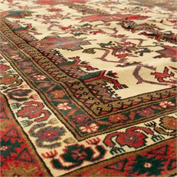 North East Persian Gochan hand-knotted rug, ivory field decorated with a vertical column of stepped polygonal medallions flanked by stylized geometric floral motifs enclosed by multiple borders incorporating rosette and reciprocal devices, in a palette of madder red, indigo, olive green, and aubergine, with cotton fringe ends  