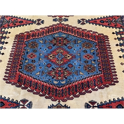 Persian rug carpet, cream ground field decorated with large red and blue central medallion and two lozenges, spandrels decorated with stylised boteh and animal motifs, floral repeating guarded border, 335cm x 253cm