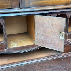 Early 19th century figured mahogany bureau bookcase, projecting splay moulded cornice over three adjustable shelves enclosed by two glazed doors, fall front revealing pigeonholes, cupboard and drawers, pull-out strays with scroll carved terminals, double cupboard with two panelled doors, on turned feet 